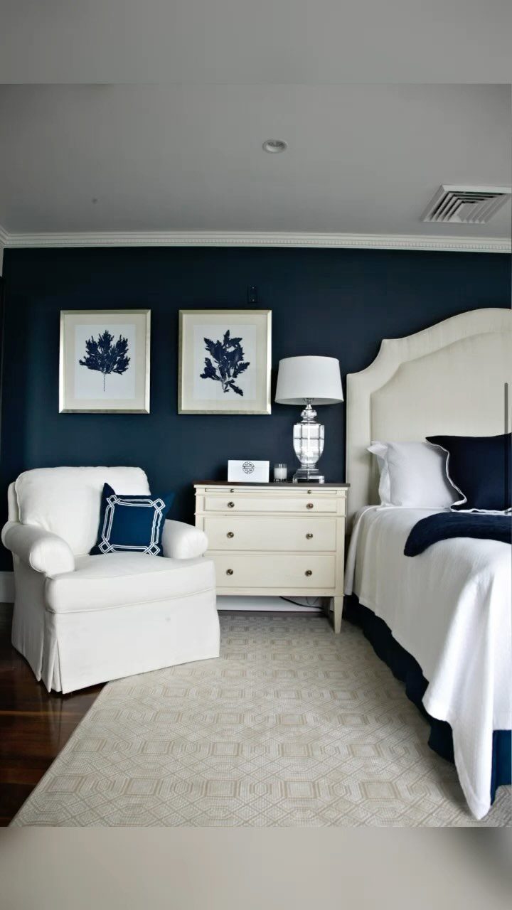 A navy blue accent wall in a bedroom with white furniture and decor.