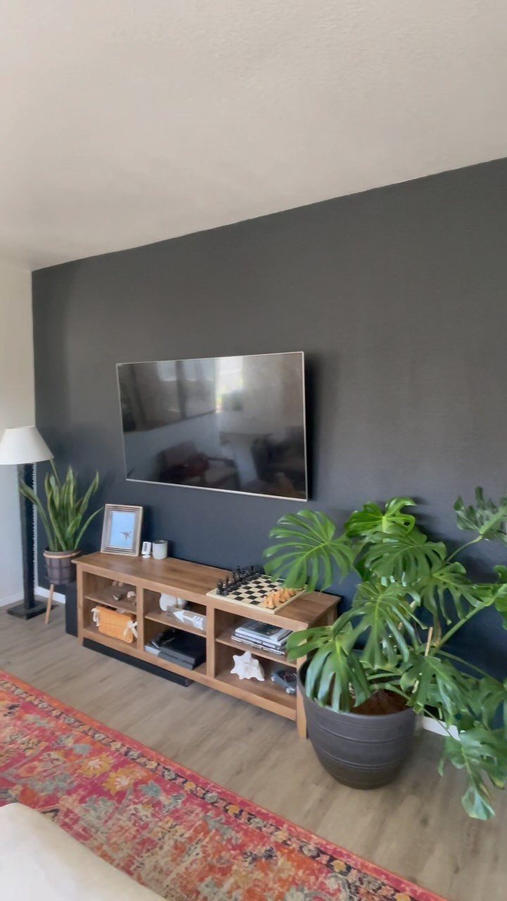 Charcoal grey accent wall with a mounted television and wooden media console below.