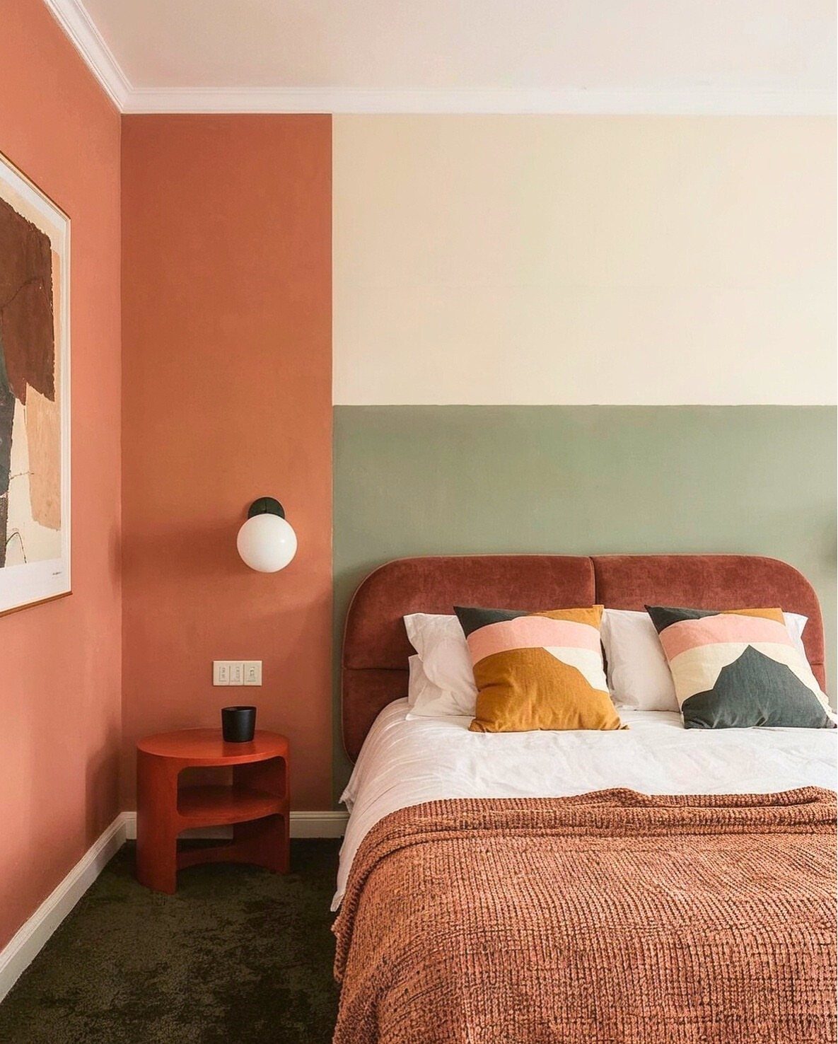 A bedroom with a color-blocked accent wall in cream, sage, and terracotta tones.