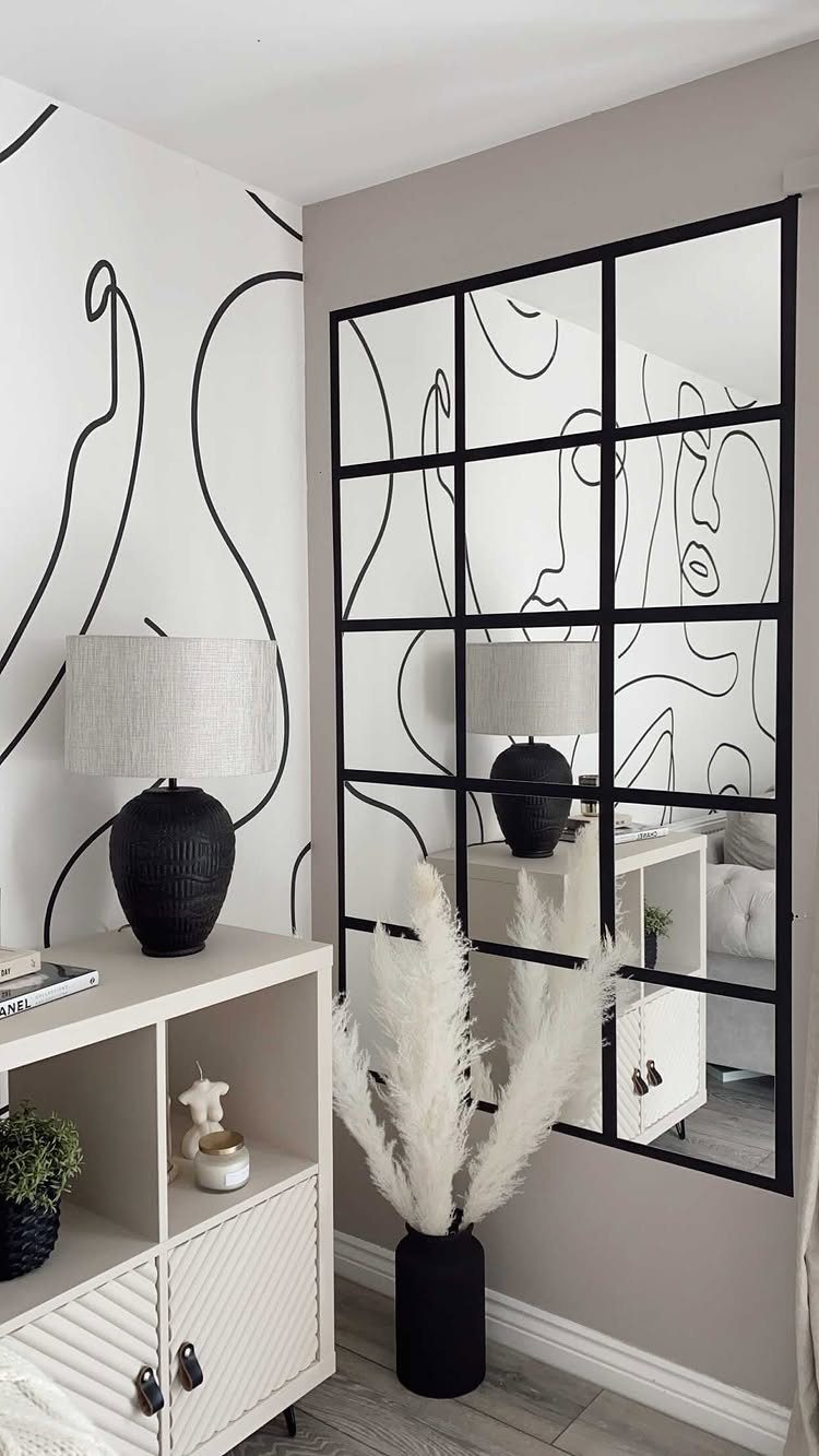 Black line-art mural on a white wall next to a large black-framed mirror.