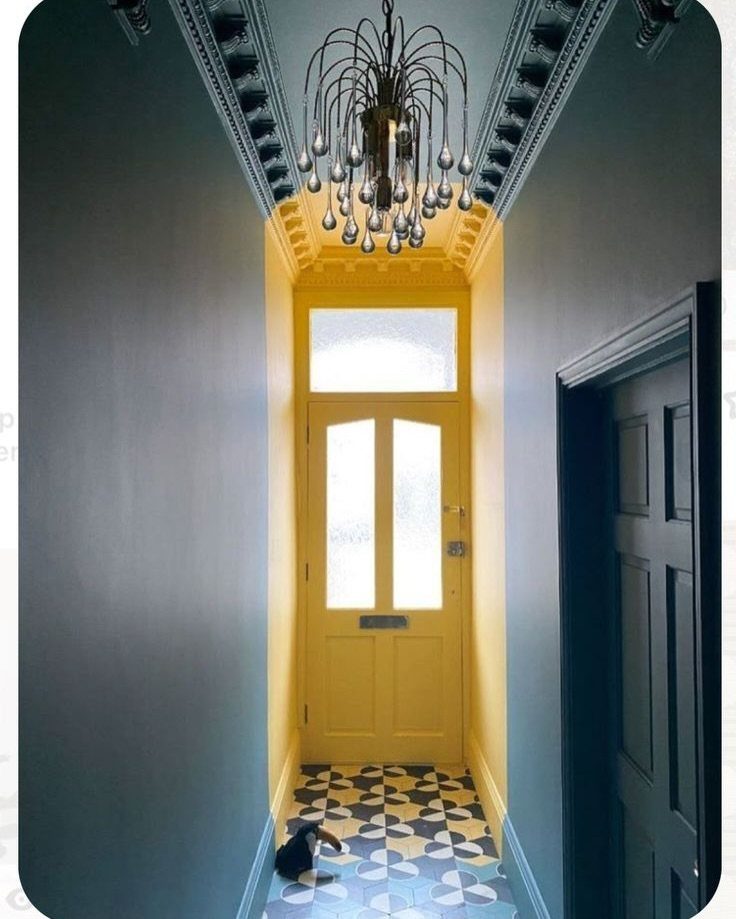 A blue hallway leading to a bright yellow accent wall and matching yellow front door.