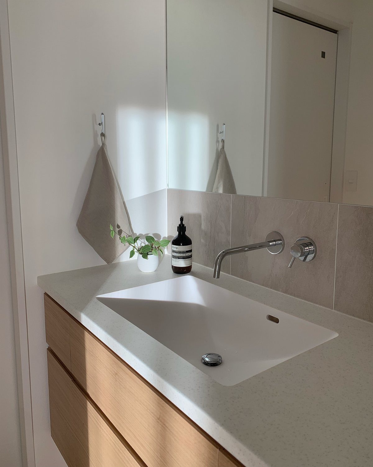 14 Bathroom Small Space Storage Ideas That Actually Fit 12 A chrome wall-mounted faucet and control knob installed above a white rectangular bathroom sink.
