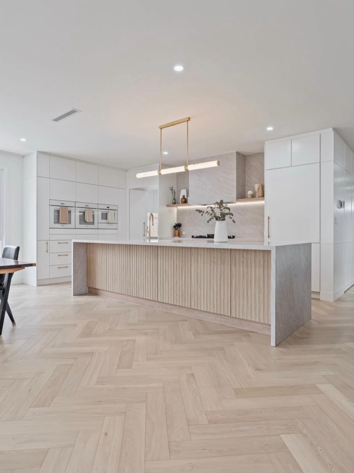 Light wood floors in a herringbone pattern within a modern, bright kitchen setting.