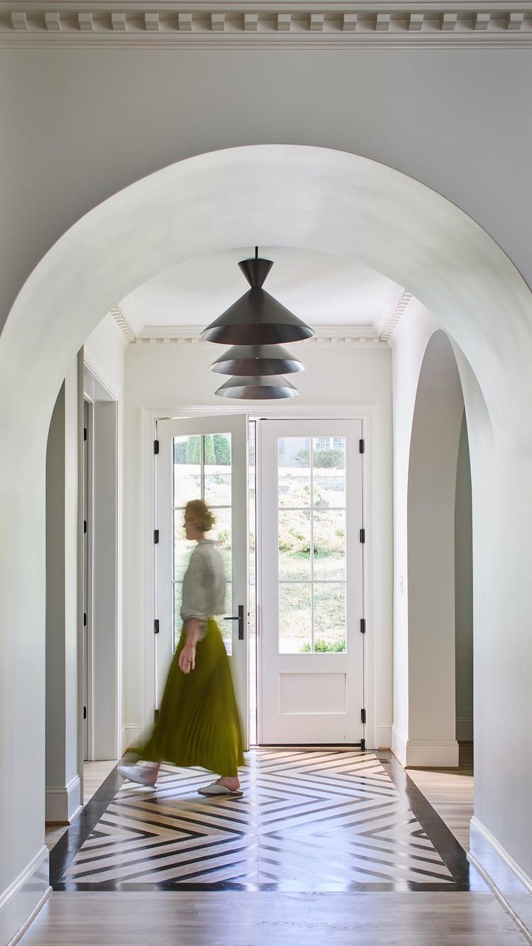 A person walking through a hallway featuring a black and white painted geometric floor pattern.