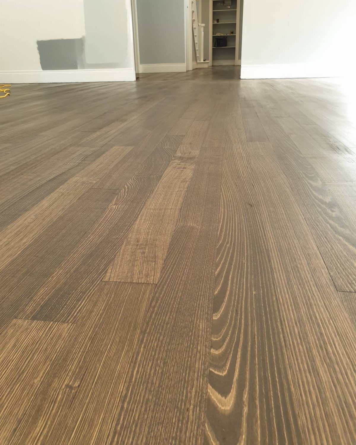 Polished hardwood floors with a smoky gray stain and visible wood grain in a bright room.