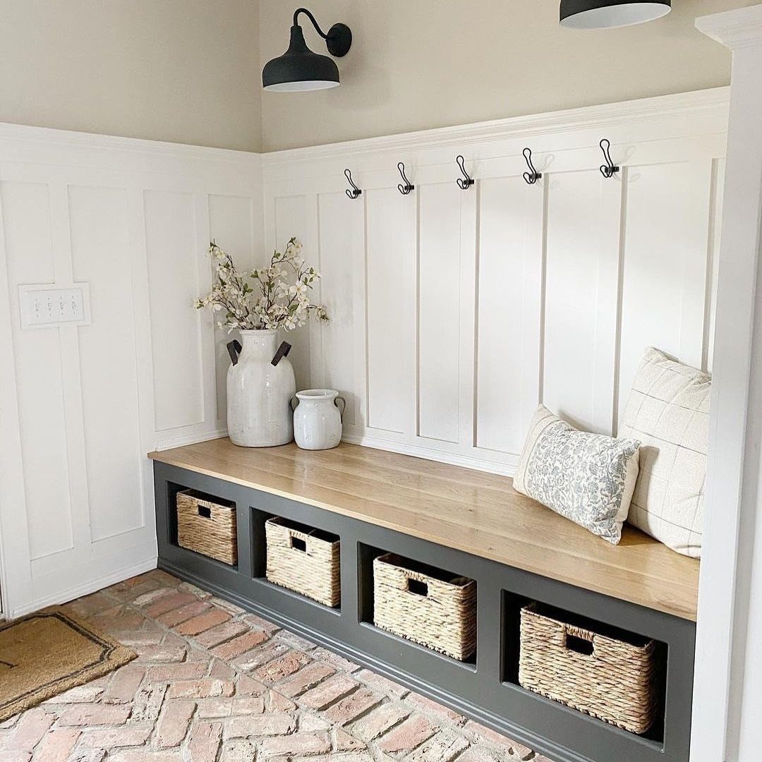 White board and batten entryway bench with wooden top and wicker storage baskets underneath.