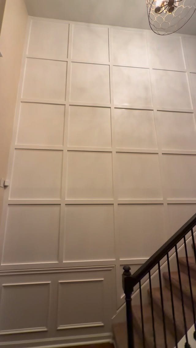 White board and batten wall with a large rectangular grid pattern next to a staircase.