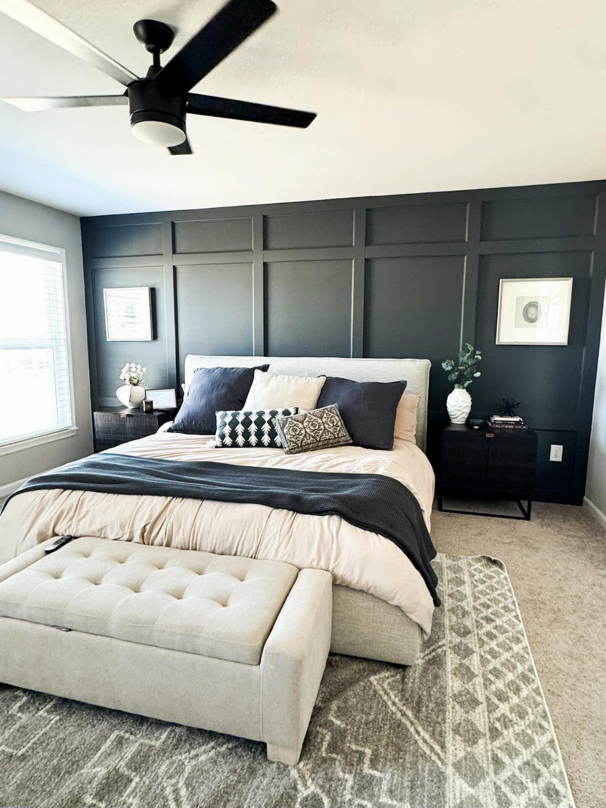 Dark charcoal board and batten paneling on a bedroom accent wall behind a large bed.