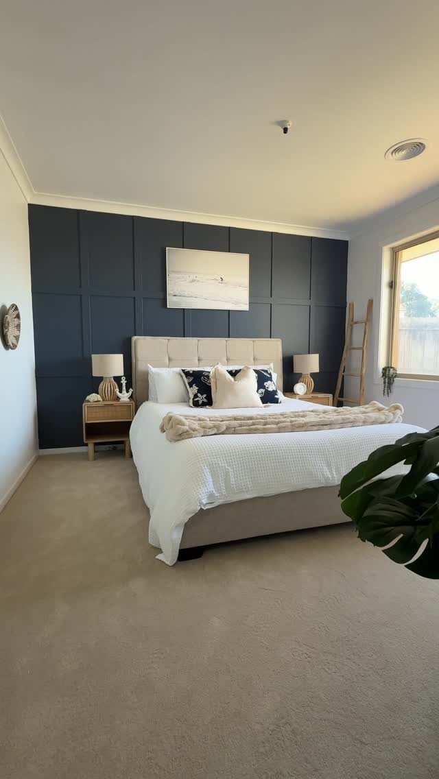 Dark blue board and batten accent wall behind a beige upholstered bed in a bedroom.