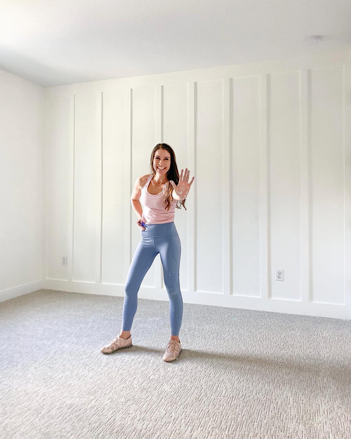 Woman standing in front of a white floor-to-ceiling board and batten accent wall.