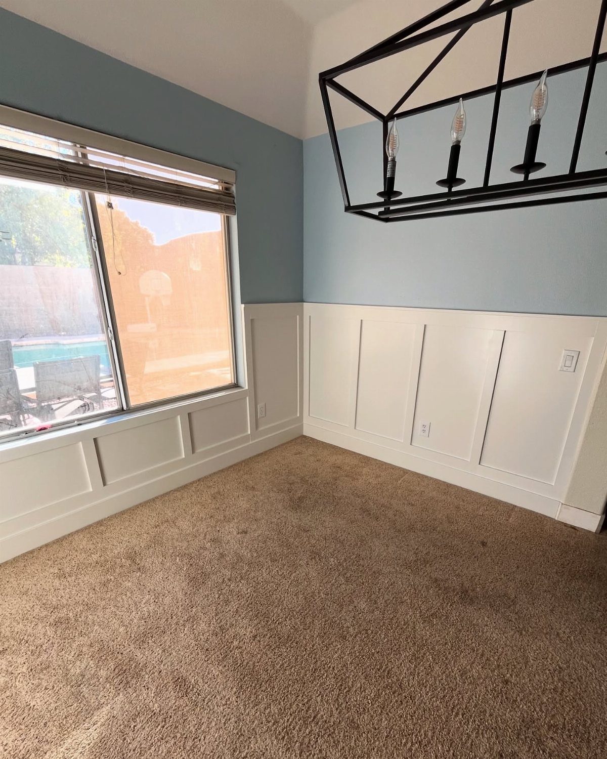 White board and batten wainscoting on the lower half of light blue walls in a carpeted room.