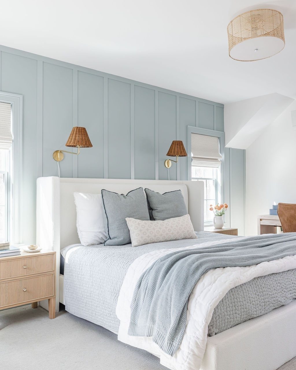 Light blue board and batten accent wall behind a white bed with neutral bedding.