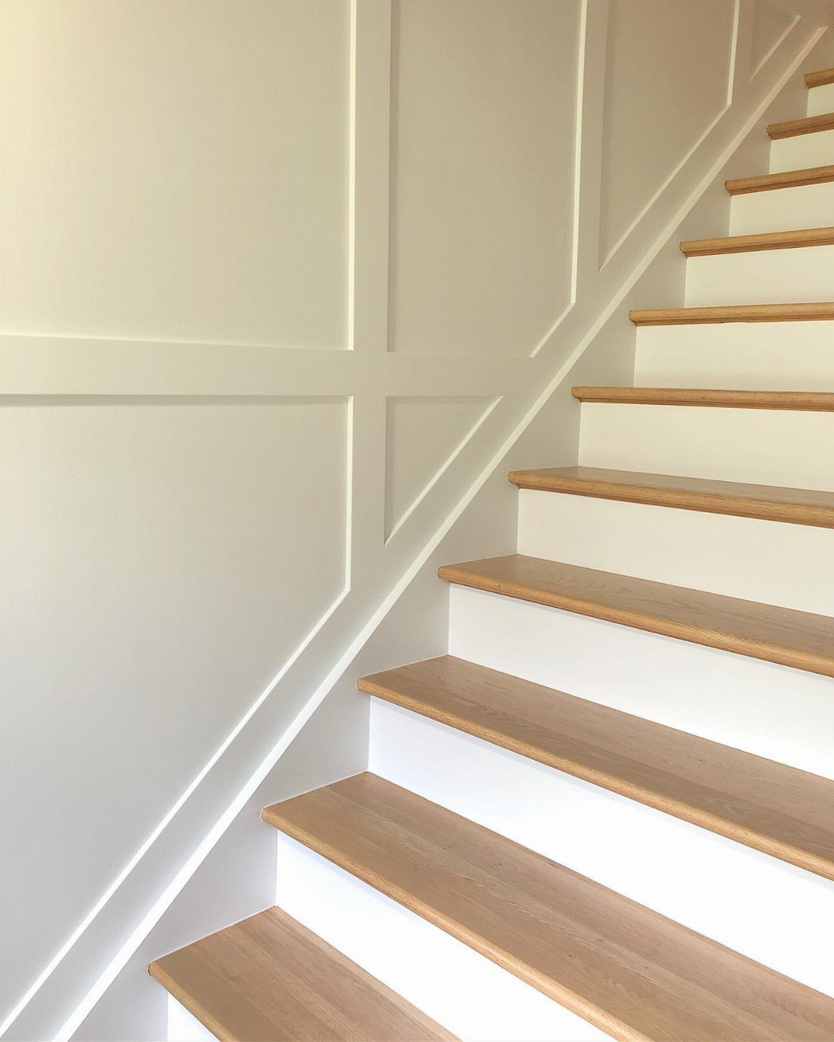 White board and batten wall panels running alongside a staircase with light wood steps.