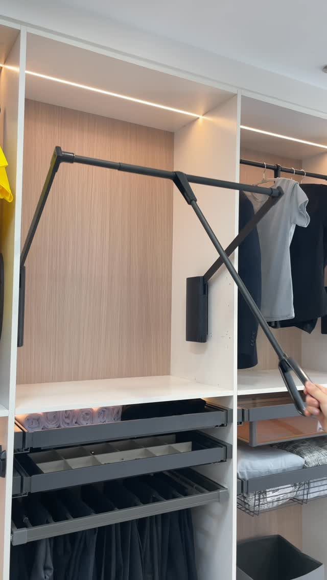 6 Closet Organization for Dresses Ideas That Save Space and Time 3 A person operates a black mechanical arm within a modern, well-lit built-in closet system.