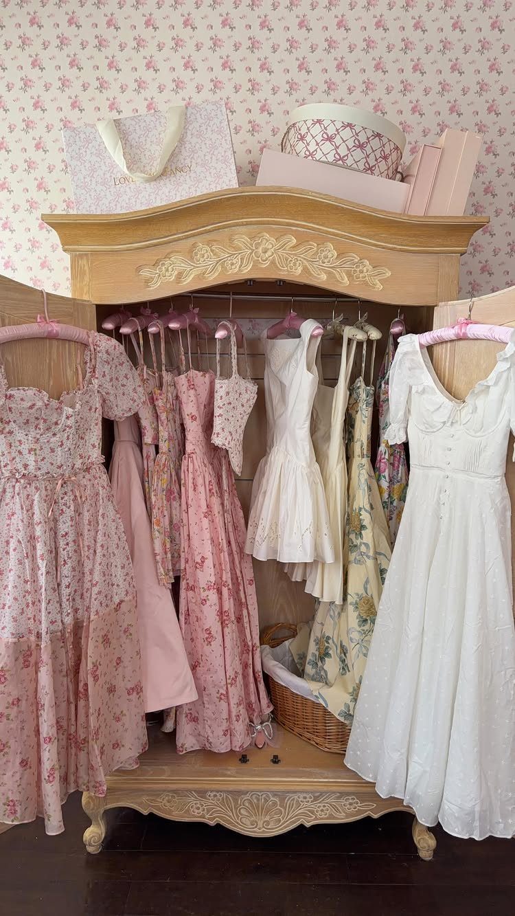 6 Closet Organization for Dresses Ideas That Save Space and Time 5 Pink and white floral dresses hanging on pink hangers inside an open wooden armoire.