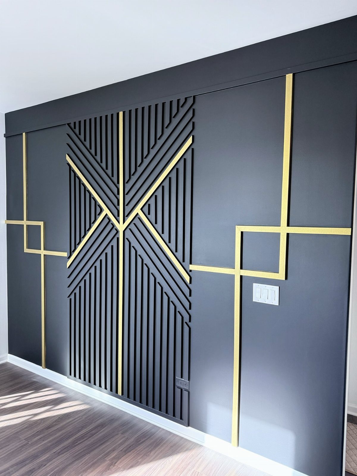 Geometric dark gray accent wall with gold metallic lines and vertical slats.