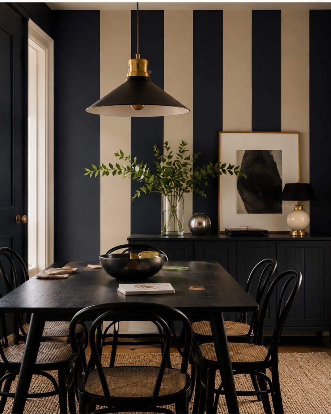 Vertical navy blue and cream striped accent wall in a dining room with black furniture.