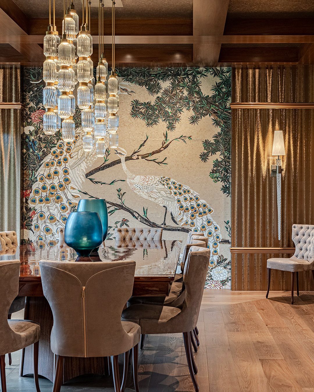 Peacock mosaic tile mural on a dining room accent wall with a crystal chandelier.