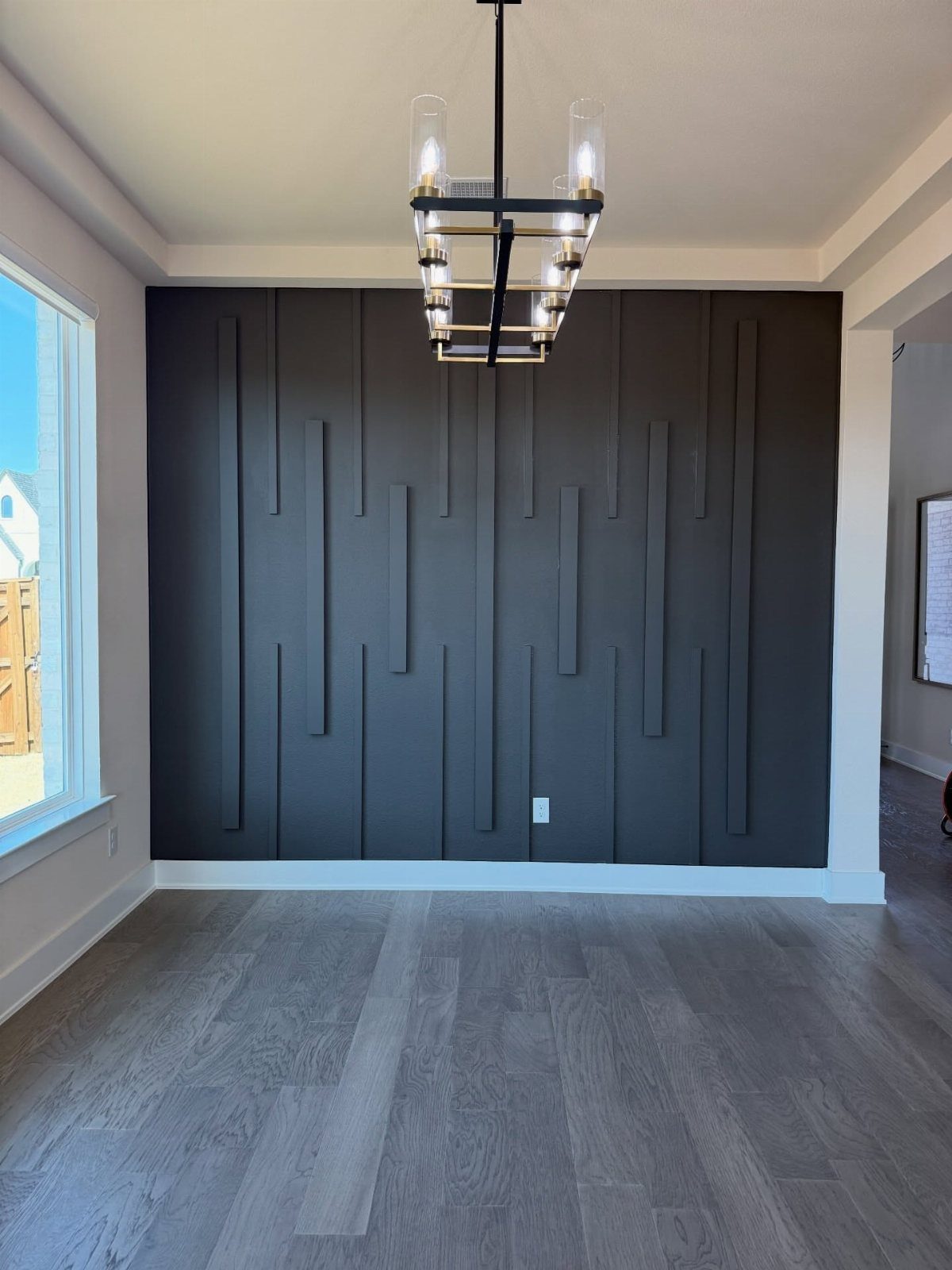 Dark charcoal gray accent wall with vertical wooden slats in a modern dining room.