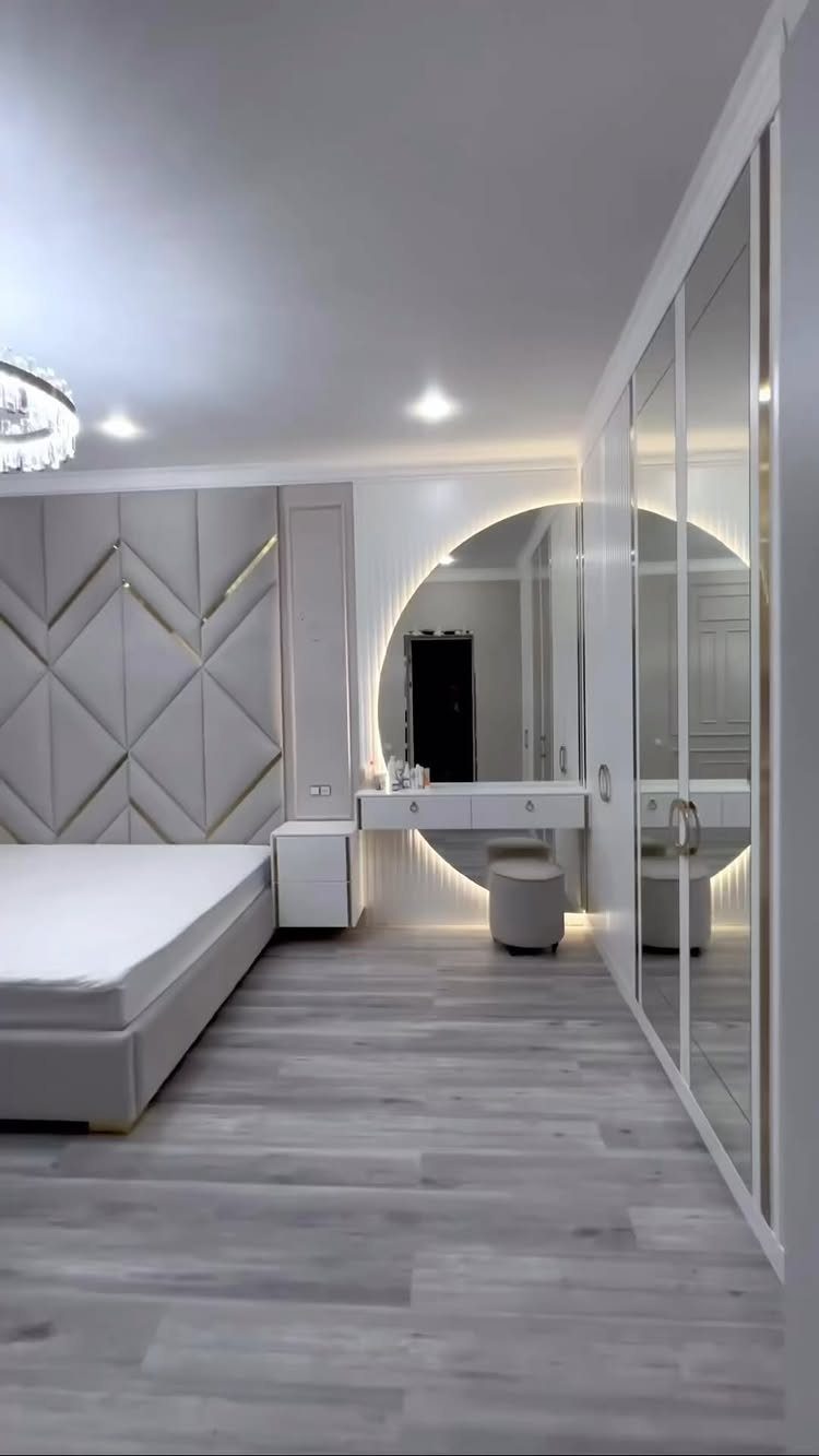 Light grey wood plank flooring in a modern bedroom with a white bed and vanity.