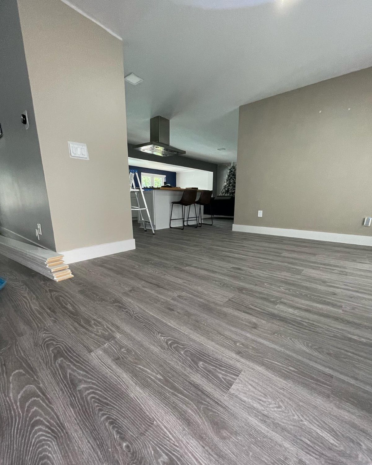 Grey wood-look flooring installed in a modern room with light grey walls and white baseboards.