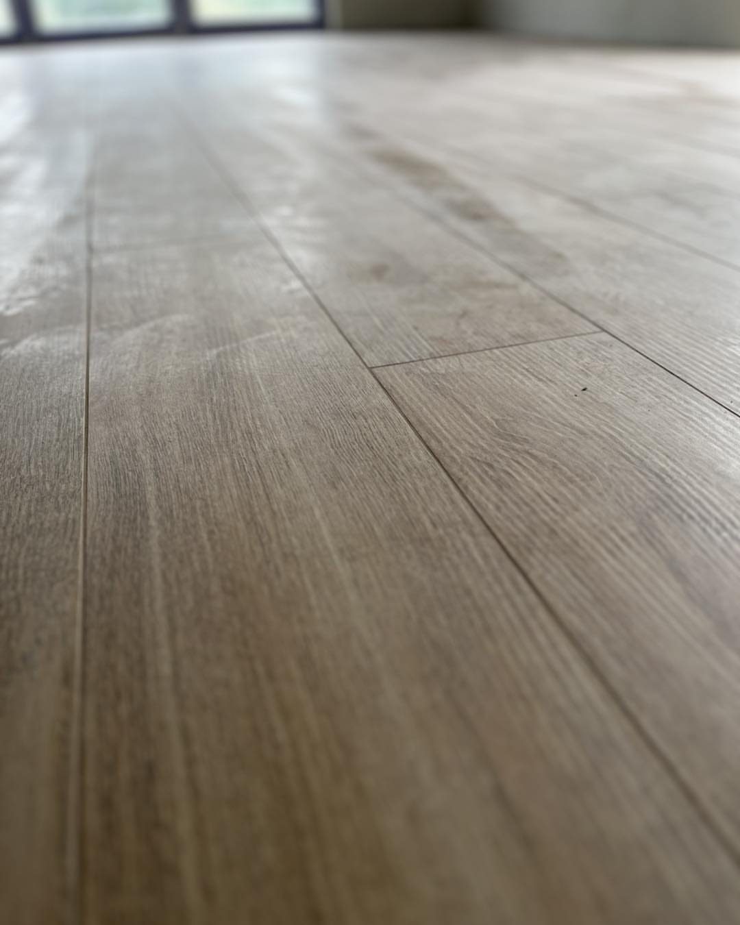 Light-colored wood flooring planks with a warm greige finish and visible natural grain texture.
