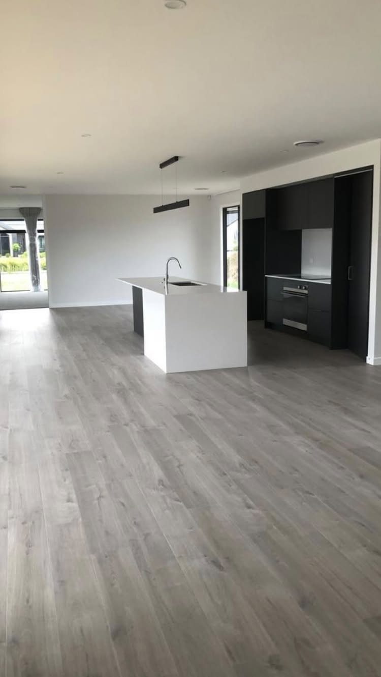 Light grey wood flooring in a modern open-plan kitchen with a white island.