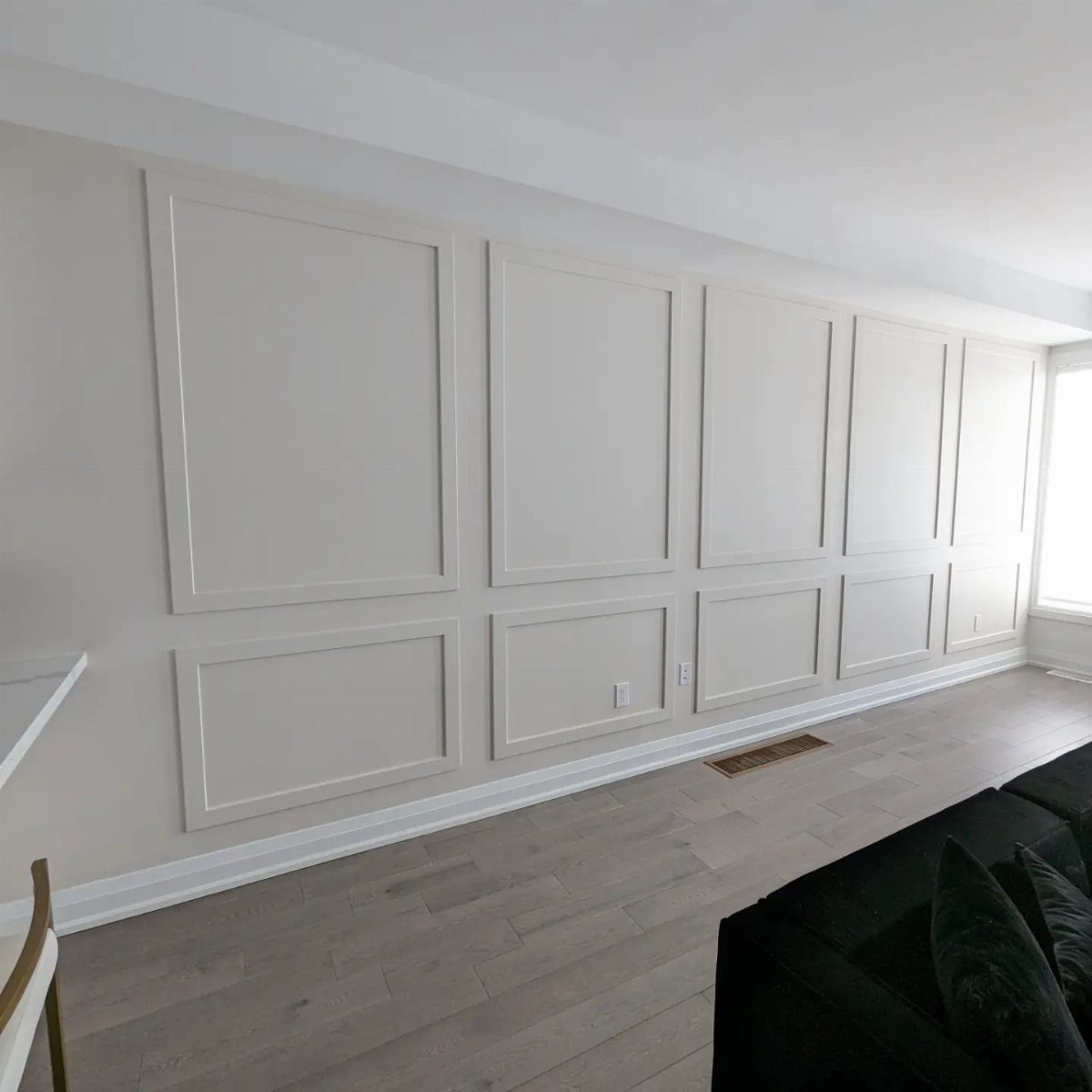 Decorative beige wall with large rectangular picture frame molding and wainscoting in a modern room.