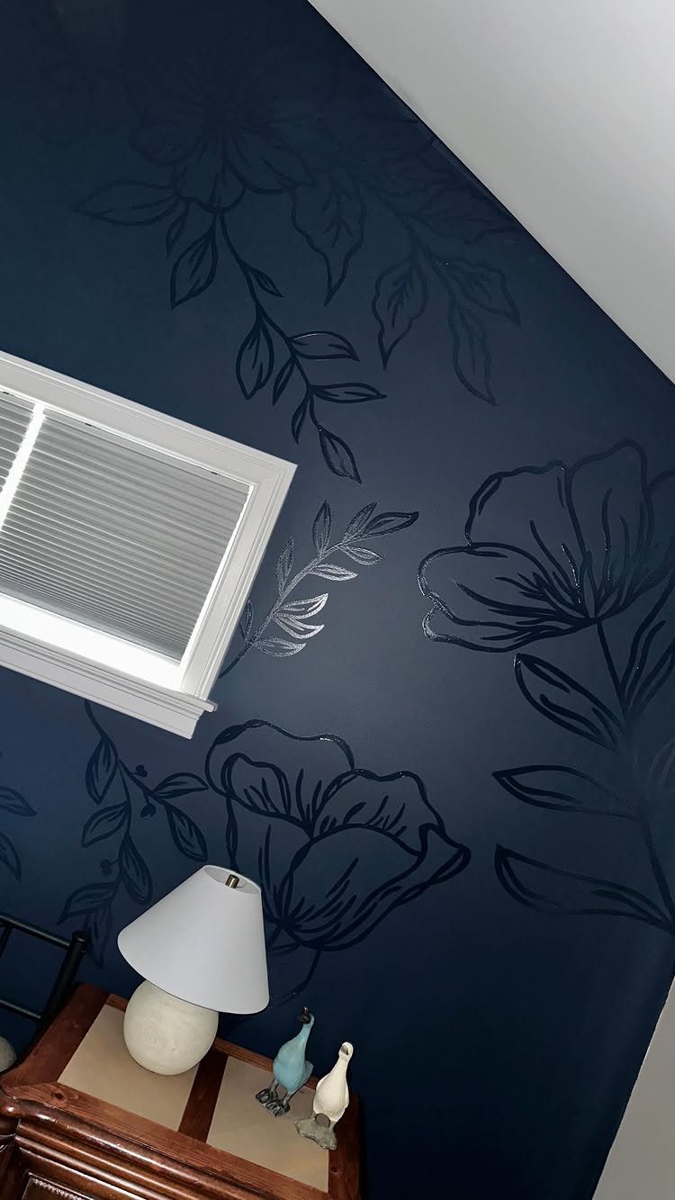 Navy blue wall decorated with large, dark floral and leaf stencil patterns.
