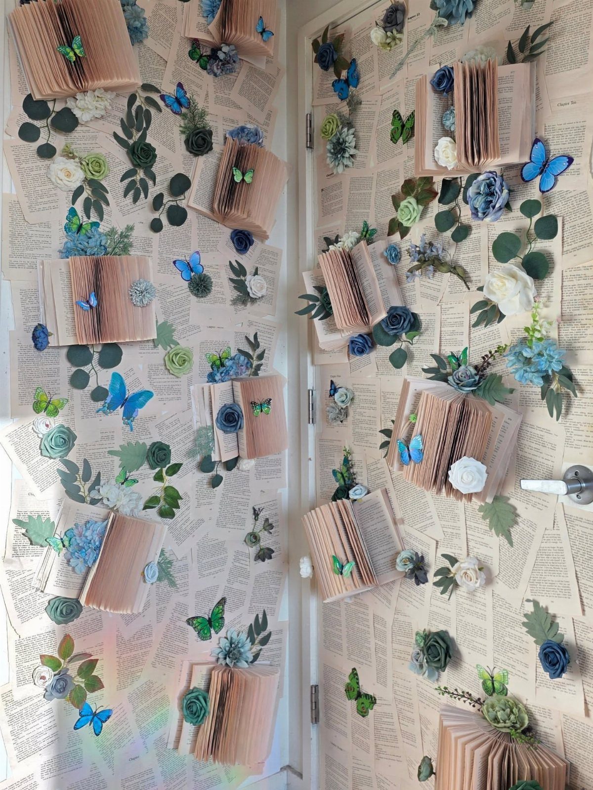 Vintage book pages covering a wall decorated with open books, flowers, and blue butterflies.