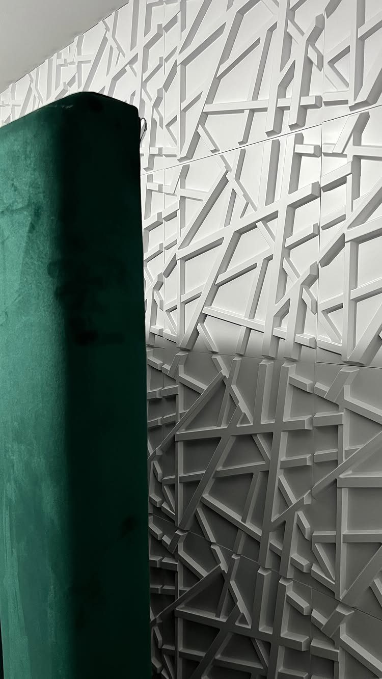 White geometric 3D wall panels with a dark green velvet curtain in the foreground.