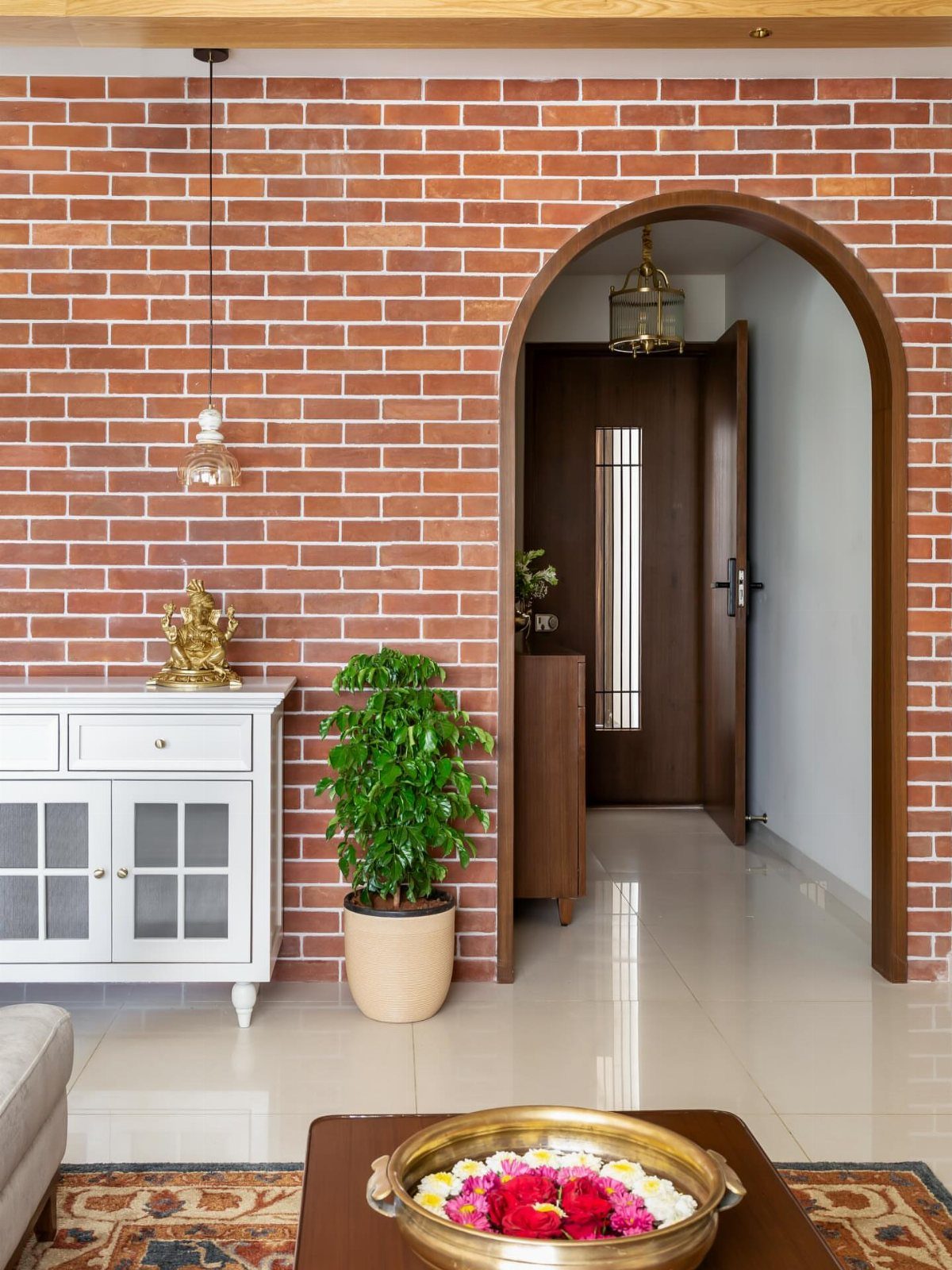 9 Interior Accent Wall Ideas with Photos 1 Red brick accent wall with an arched doorway and a white sideboard in a bright room.