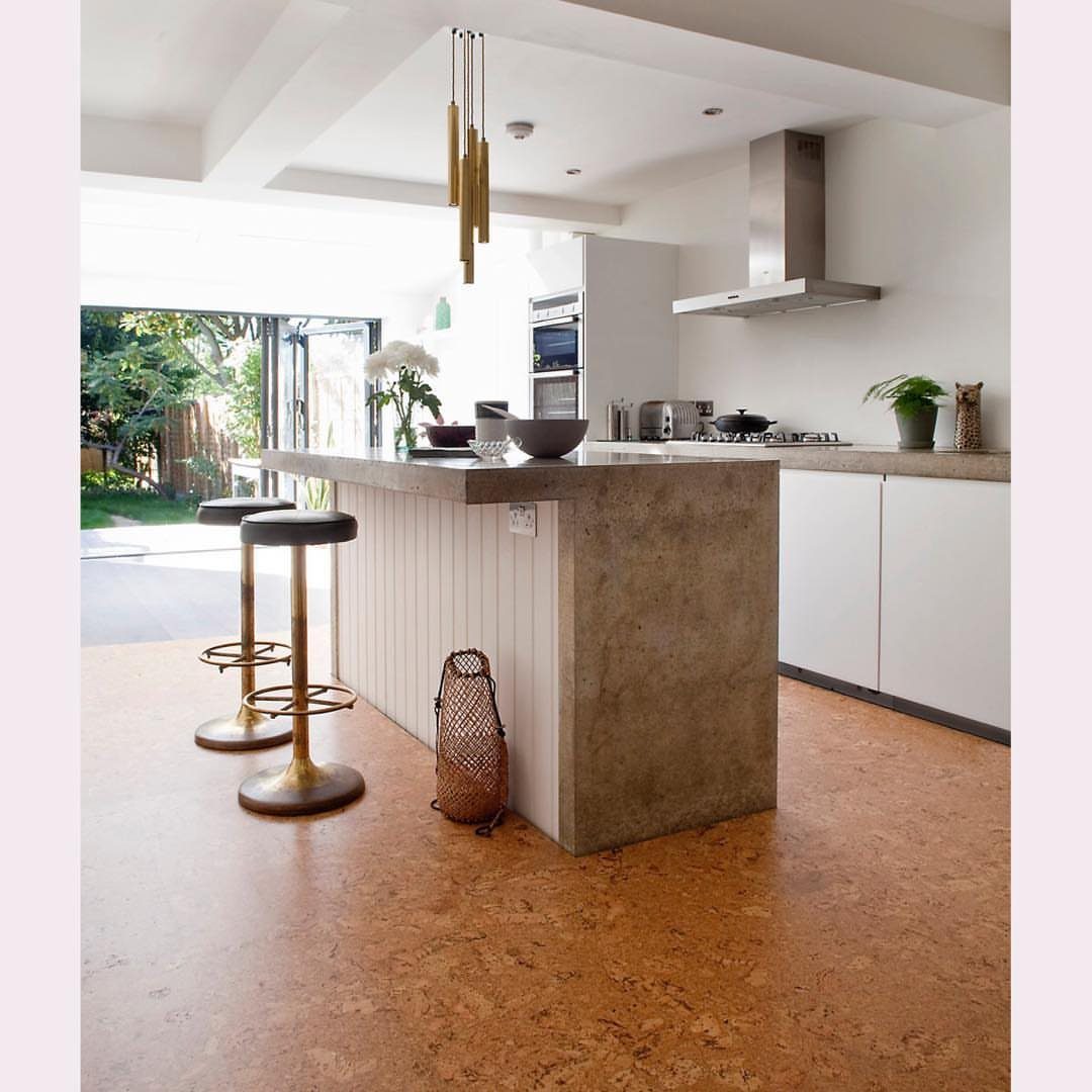 11 Kitchen Flooring Trends for 2026 That Actually Hold Up 9 A modern kitchen with a stone island and warm cork flooring throughout the room.