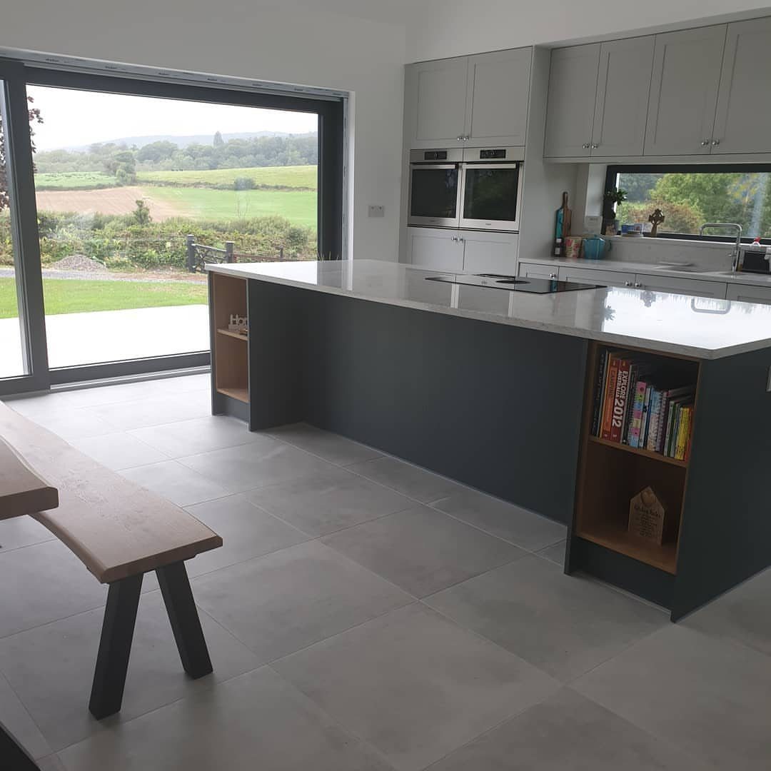 11 Kitchen Flooring Trends for 2026 That Actually Hold Up 6 Large light gray tiles cover the floor of a modern kitchen with a gray island.
