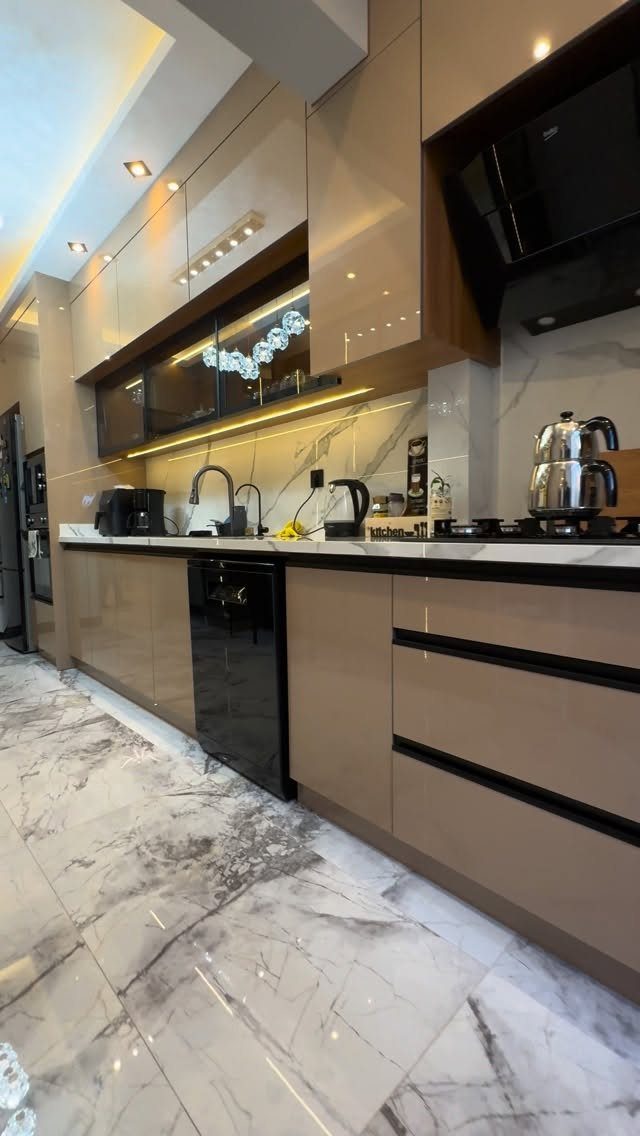 11 Kitchen Flooring Trends for 2026 That Actually Hold Up 10 White marble-patterned tiles cover the floor of a modern kitchen with taupe cabinetry.