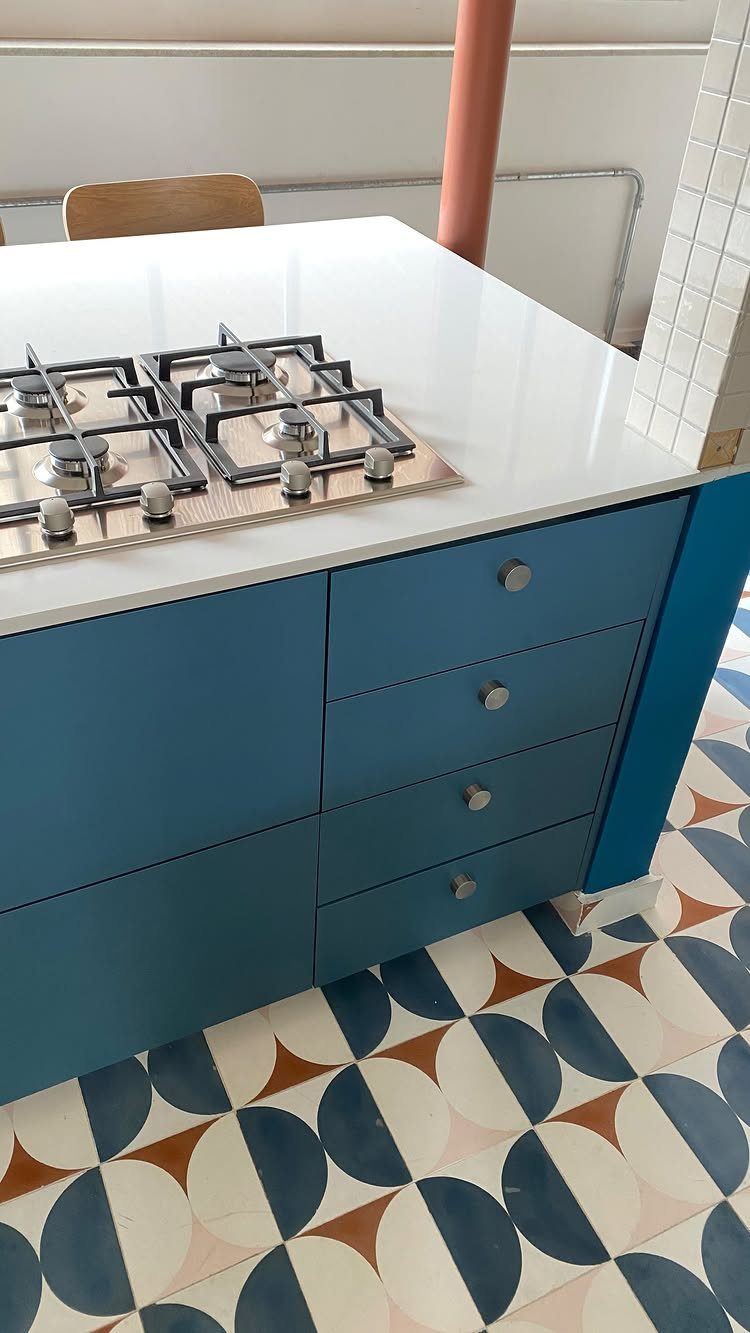 11 Kitchen Flooring Trends for 2026 That Actually Hold Up 4 Patterned geometric kitchen floor tiles in navy, terracotta, and cream beneath blue cabinetry.