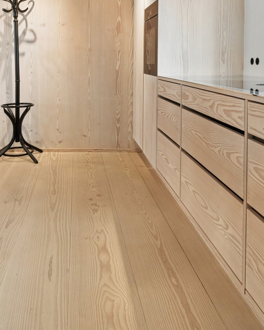 11 Kitchen Flooring Trends for 2026 That Actually Hold Up 2 Wide plank light wood flooring in a minimalist room with matching wood cabinetry and walls.