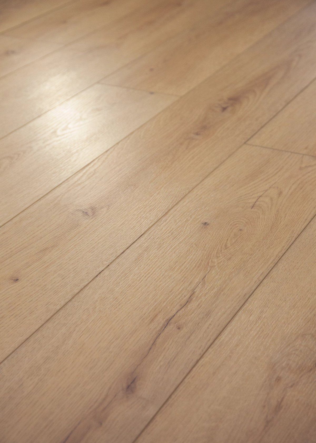 Light oak wood flooring planks featuring natural grain patterns and visible dark knots.