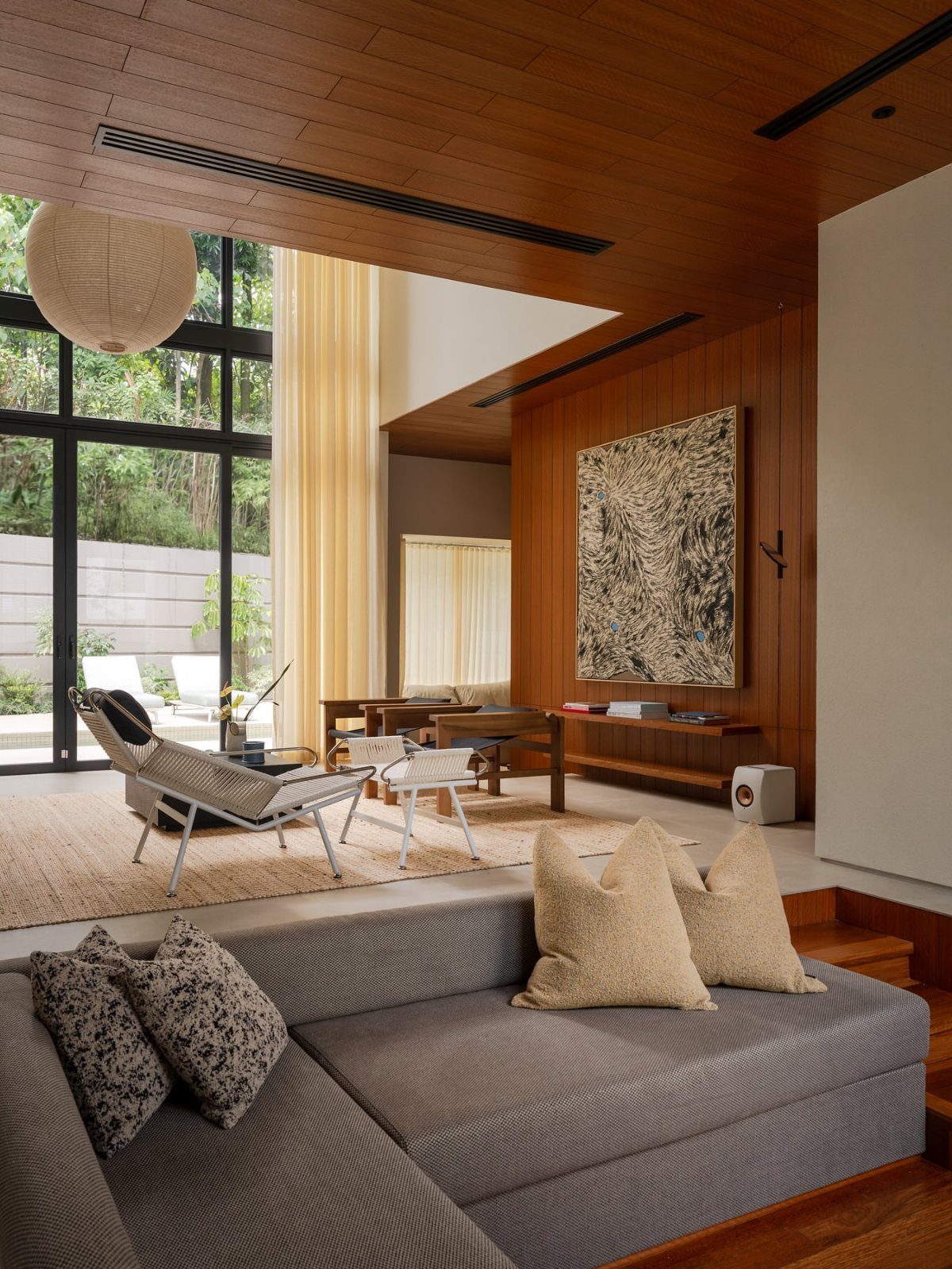 Modern living room with warm wood paneling on the walls and ceiling, featuring mid-century furniture.