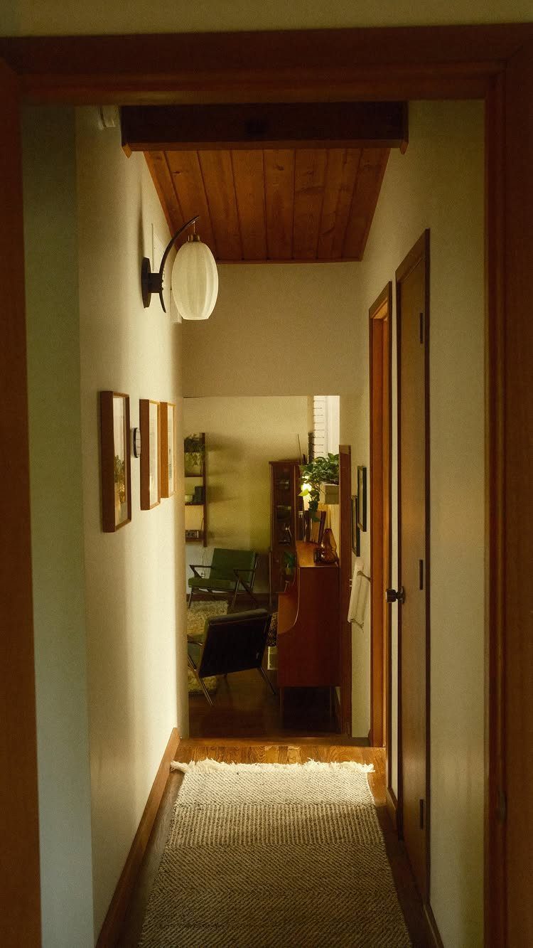 Wood paneled ceiling and a white globe light fixture in a hallway view.