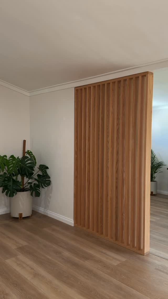 Light wood vertical slat panel acting as a room divider in a minimalist room.