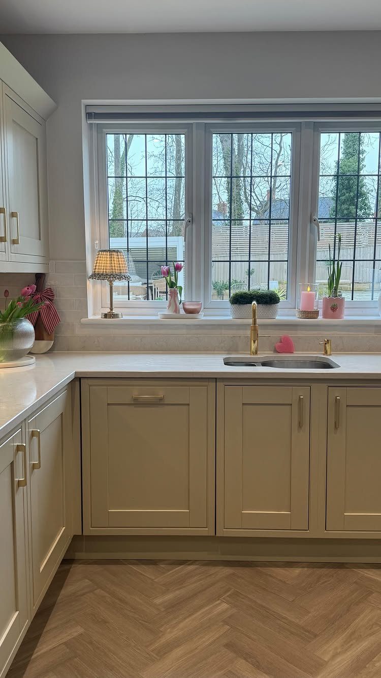 Light beige kitchen cabinets and white countertops above a light wood herringbone pattern floor.