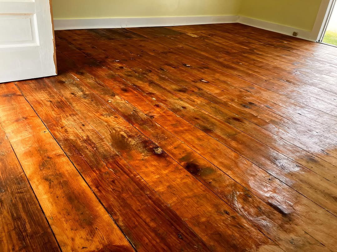 Distressed reddish-brown wide plank wooden flooring with visible knots and a weathered texture.