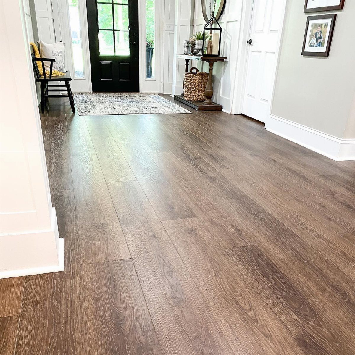 Wide plank wood flooring with a medium brown finish in a bright modern farmhouse hallway.