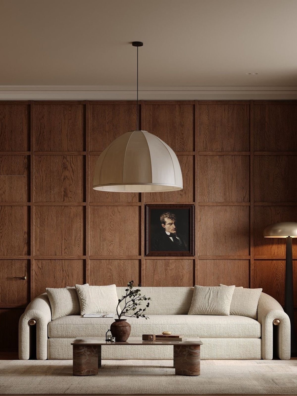 Dark wood paneled wall behind a cream sofa and a large dome pendant light in a living room.