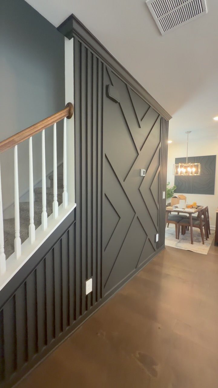 Dark grey accent wall with vertical slats and a large geometric pattern in a hallway.