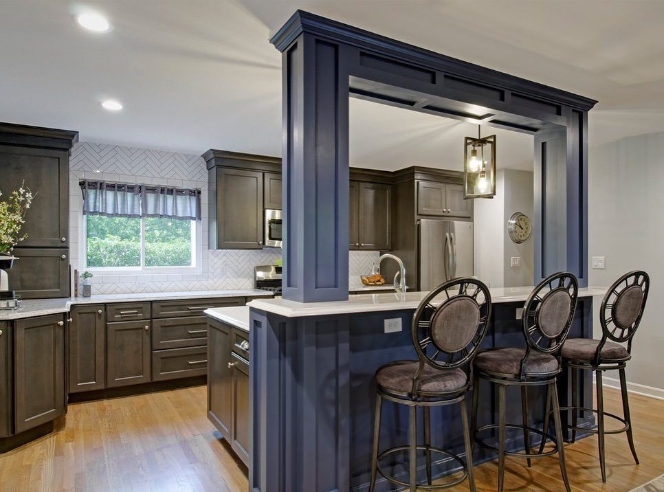 Navy blue kitchen island with a two-tiered white countertop and three dark bar stools.