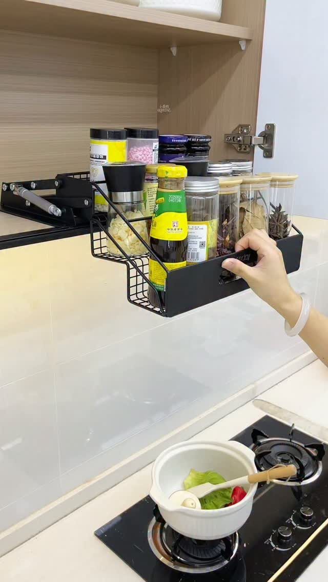 Pull Down Upper Cabinet: 5 Storage Solutions That Actually Work 1 A hand pulling down a black metal spice rack from an upper kitchen cabinet.