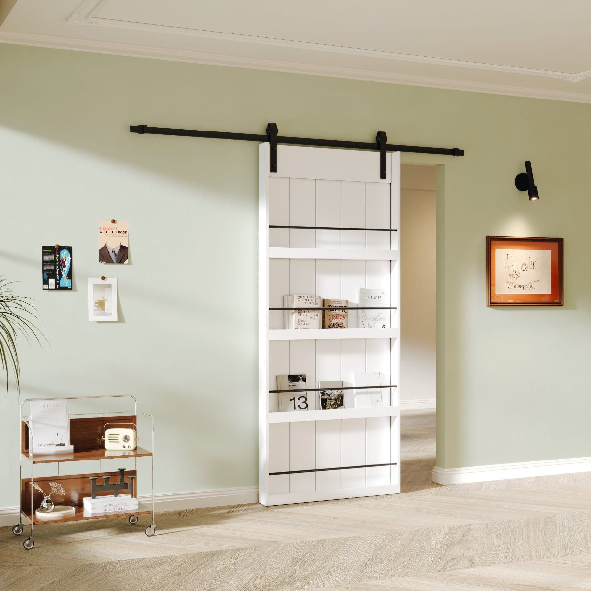A white sliding barn door with black shelves holding books against a light green wall.