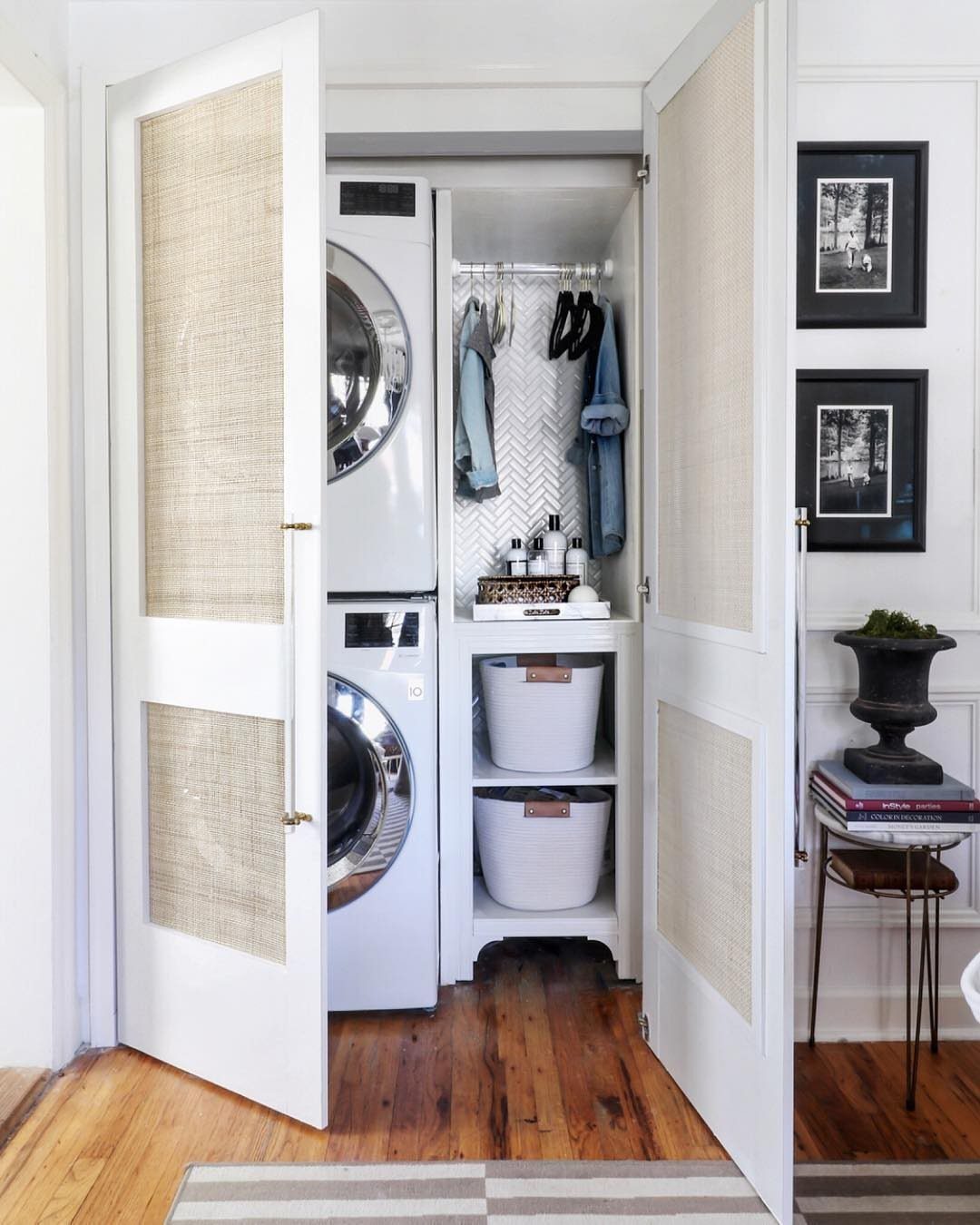 10 Small Laundry Closet Ideas That Actually Fit in a Hallway 1 White laundry closet featuring a washer, dryer, hanging clothes, and white storage baskets on shelves.